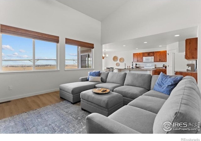 1718 101st Avenue Ct, Greeley, CO 80634 - living room featuring light wood finished floors, baseboards, recessed lighting, a chandelier, and a high ceiling