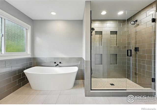 2133 Indian Peaks Cir, Longmont, CO 80504 - full bath with a stall shower, a soaking tub, tile walls, tile patterned flooring, and recessed lighting