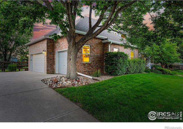2133 Indian Peaks Cir, Longmont, CO 80504 - view of property hidden behind natural elements with driveway, a front lawn, a garage, brick siding, and a shingled roof