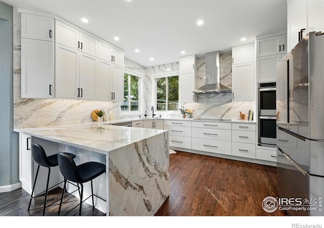 2133 Indian Peaks Cir, Longmont, CO 80504 - kitchen with wall chimney range hood, stainless steel appliances, a peninsula, backsplash, and recessed lighting