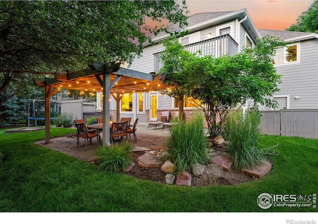 2133 Indian Peaks Cir, Longmont, CO 80504 - back of property at dusk with a trampoline, a patio, and a pergola