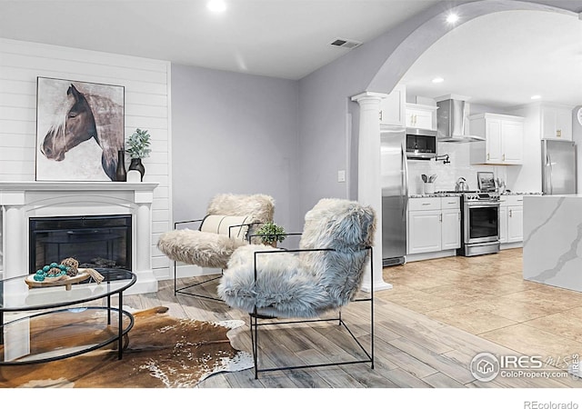 9139 County Road 54, Milliken, CO 80543 - living area with arched walkways, recessed lighting, a glass covered fireplace, and light wood-style flooring