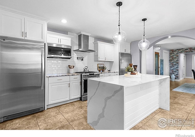 9139 County Road 54, Milliken, CO 80543 - kitchen with appliances with stainless steel finishes, wall chimney exhaust hood, arched walkways, decorative backsplash, and a center island