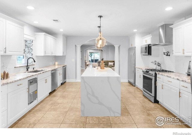 9139 County Road 54, Milliken, CO 80543 - kitchen with a sink, stainless steel appliances, wall chimney range hood, arched walkways, and a center island
