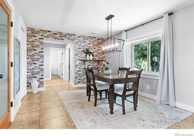 9139 County Road 54, Milliken, CO 80543 - dining room with a chandelier, light tile patterned flooring, brick wall, and baseboards