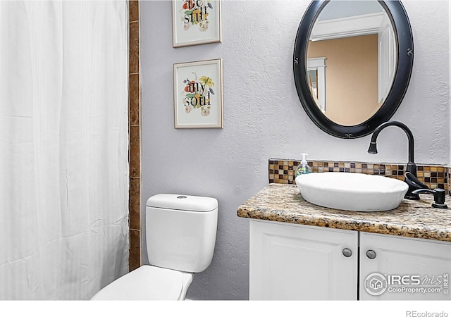 9139 County Road 54, Milliken, CO 80543 - full bath with decorative backsplash, vanity, toilet, a textured wall, and a shower with curtain