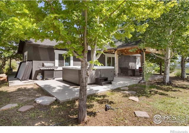 9139 County Road 54, Milliken, CO 80543 - rear view of house featuring a hot tub, a patio, and stucco siding