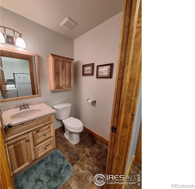 56 Pamlico Ct, Red Feather Lakes, CO 80545 - bathroom featuring vanity, baseboards, washer / dryer, toilet, and stone finish floors