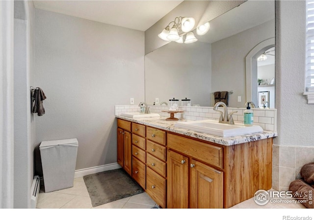 5895 E Conservation Dr, Frederick, CO 80504 - full bath with double vanity, tile patterned floors, a baseboard radiator, toilet, and a chandelier