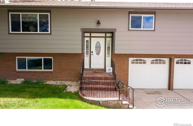 204 35th St SW, Loveland, CO 80537 - property entrance featuring driveway, a garage, brick siding, and a yard