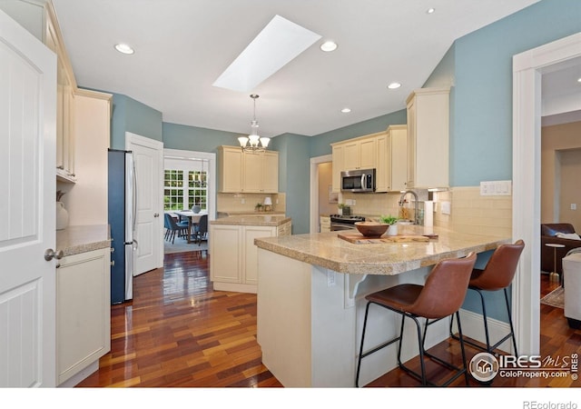1926 Crested Butte Ct, Loveland, CO 80538 - kitchen with stainless steel appliances, a peninsula, a skylight, dark wood-type flooring, and light countertops