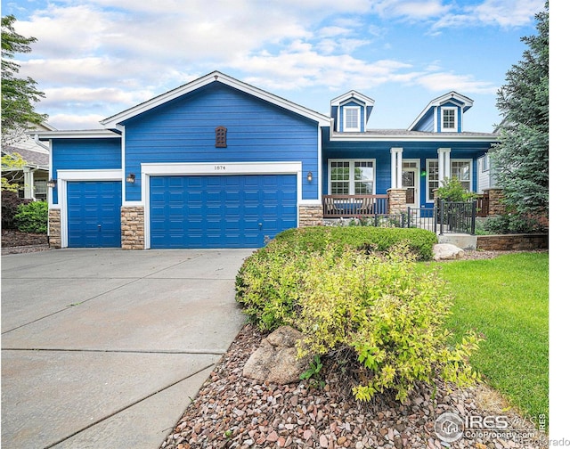 1874 Ute Creek Dr, Longmont, CO 80504 - view of front of house with stone siding, a porch, an attached garage, and driveway