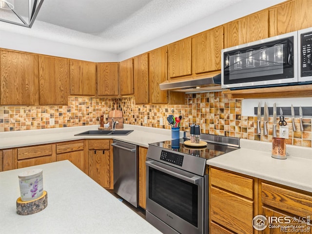 838 Vista Ln, Estes Park, CO 80517 - kitchen featuring stainless steel appliances, a sink, under cabinet range hood, light countertops, and decorative backsplash