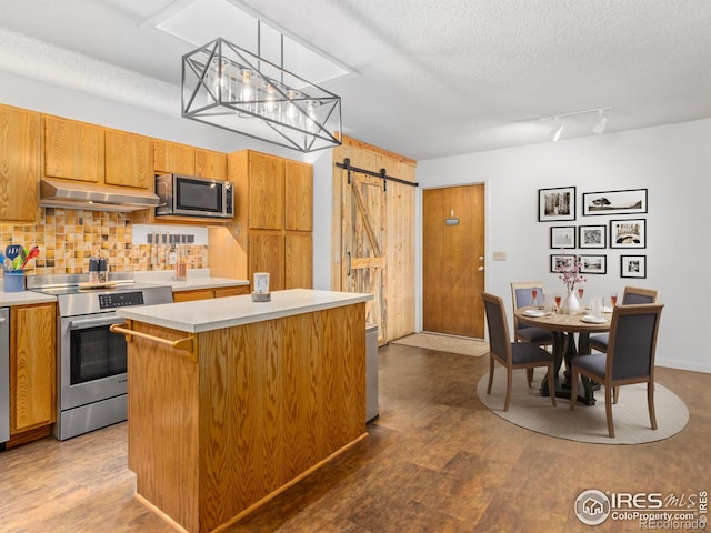 838 Vista Ln, Estes Park, CO 80517 - kitchen with stainless steel appliances, a barn door, light countertops, under cabinet range hood, and a kitchen island