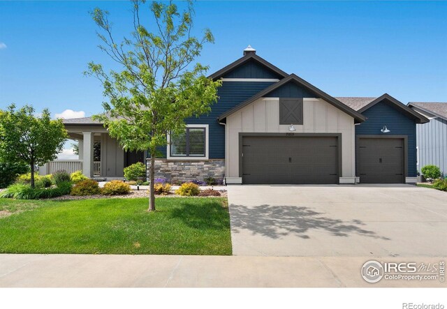 7015 Toponas Ct, Timnath, CO 80547 - view of front facade with a garage, a front yard, concrete driveway, board and batten siding, and stone siding
