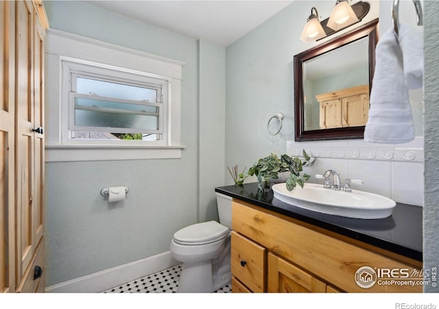 729 Peterson St, Fort Collins, CO 80524 - bathroom with toilet, vanity, decorative backsplash, and baseboards