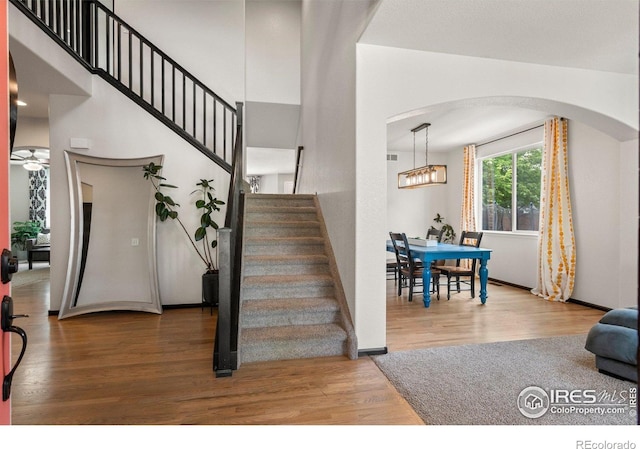 1682 Crestview Ln, Erie, CO 80516 - entrance foyer featuring arched walkways, stairway, wood finished floors, a chandelier, and a high ceiling