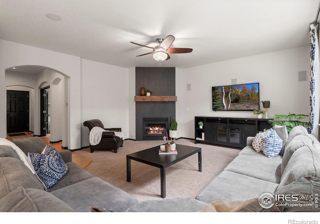 1682 Crestview Ln, Erie, CO 80516 - carpeted living area featuring ceiling fan, arched walkways, and a large fireplace