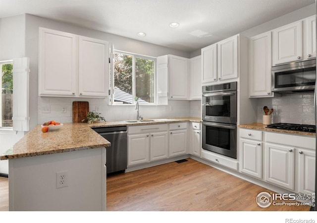 1682 Crestview Ln, Erie, CO 80516 - kitchen with stainless steel appliances, a sink, decorative backsplash, a peninsula, and white cabinets