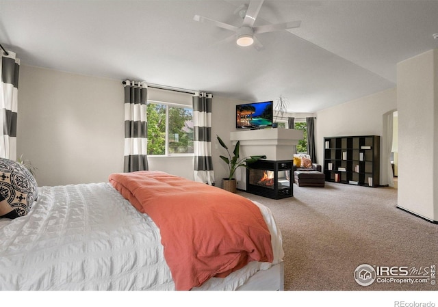 1682 Crestview Ln, Erie, CO 80516 - carpeted bedroom featuring multiple windows, a multi sided fireplace, vaulted ceiling, and ceiling fan