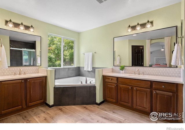 1682 Crestview Ln, Erie, CO 80516 - ensuite bathroom with wood finished floors, tasteful backsplash, two vanities, and a garden tub