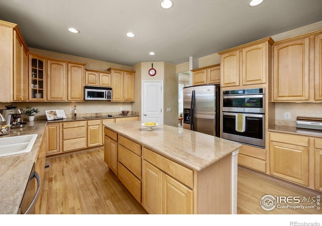 14246 Piney River Rd, Broomfield, CO 80023 - kitchen featuring appliances with stainless steel finishes, light brown cabinets, a center island, light wood-style flooring, and recessed lighting
