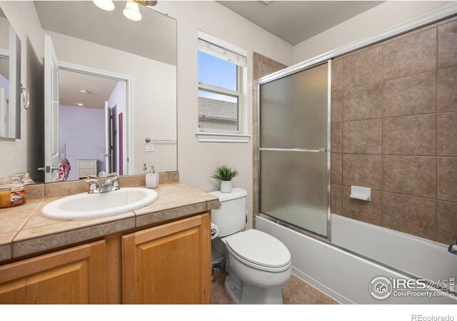 14246 Piney River Rd, Broomfield, CO 80023 - bathroom featuring vanity, toilet, shower / bath combination with glass door, and tile patterned floors
