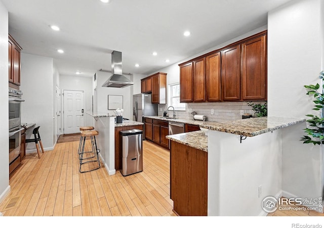 4039 N Clay St, Denver, CO 80211 - kitchen with island exhaust hood, a kitchen bar, a sink, backsplash, and stainless steel appliances