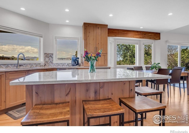 1067 W Alder St, Louisville, CO 80027 - kitchen with recessed lighting, light stone counters, a kitchen island, light wood finished floors, and tasteful backsplash