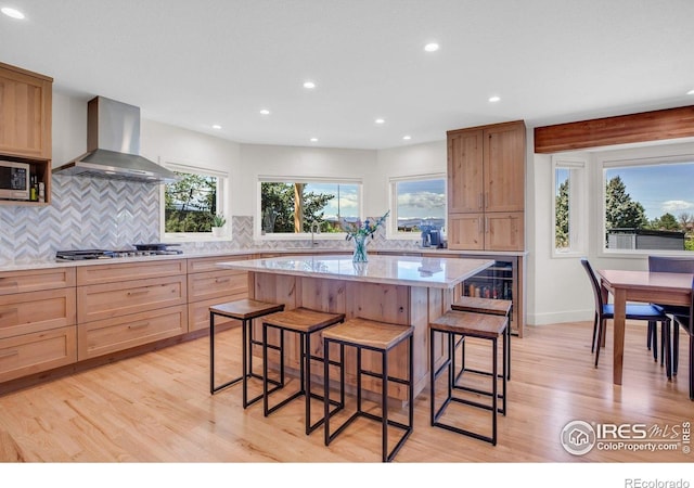 1067 W Alder St, Louisville, CO 80027 - kitchen with wall chimney exhaust hood, a kitchen breakfast bar, light wood finished floors, stainless steel appliances, and recessed lighting