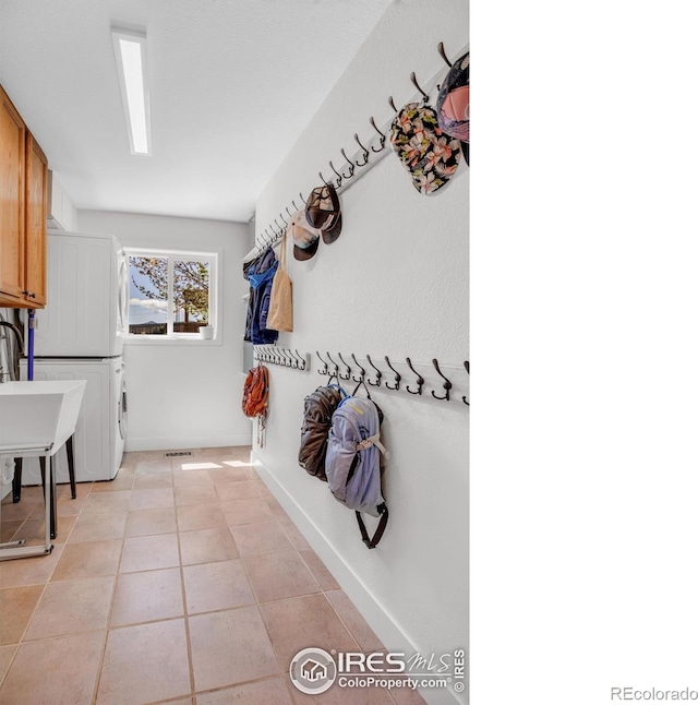 1067 W Alder St, Louisville, CO 80027 - laundry room with cabinet space, stacked washing machine and dryer, and light tile patterned flooring