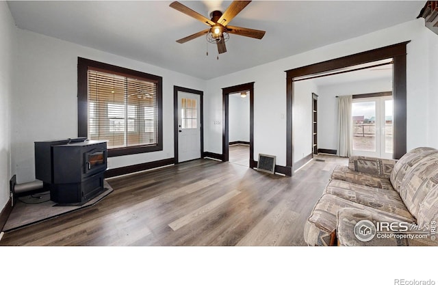 9571 Gray Ave, Carr, CO 80612 - living room featuring a wood stove, wood finished floors, ceiling fan, and baseboards