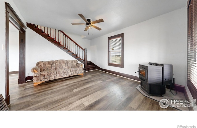 9571 Gray Ave, Carr, CO 80612 - unfurnished living room featuring a wood stove, stairway, a ceiling fan, wood finished floors, and baseboards