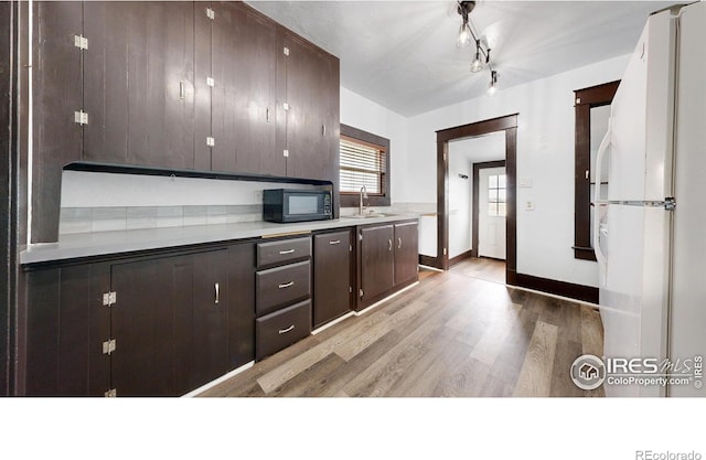 9571 Gray Ave, Carr, CO 80612 - kitchen with freestanding refrigerator, light wood-type flooring, dark brown cabinets, and a sink