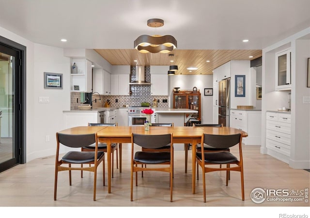 1579 W Costilla Pl, Littleton, CO 80120 - kitchen with wall chimney range hood, appliances with stainless steel finishes, white cabinets, decorative backsplash, and recessed lighting