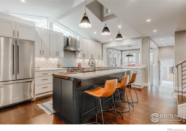 1816 Mariposa Ave, Boulder, CO 80302 - kitchen with high end refrigerator, wall chimney range hood, dark wood finished floors, tasteful backsplash, and an island with sink