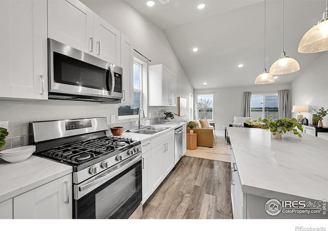 403 Pony Express Trl, Ault, CO 80610 - kitchen with appliances with stainless steel finishes, a sink, vaulted ceiling, open floor plan, and white cabinetry