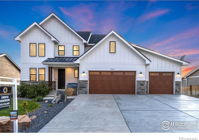 7061 Sage Meadows Dr, Wellington, CO 80549 - view of front of home featuring stone siding, a standing seam roof, concrete driveway, and a garage