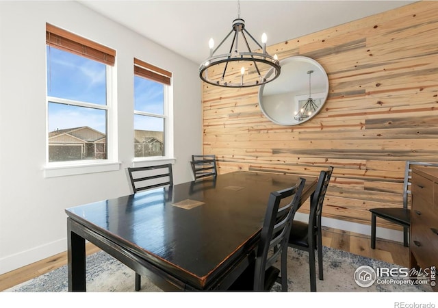 7061 Sage Meadows Dr, Wellington, CO 80549 - dining area with a chandelier, wooden walls, baseboards, and wood finished floors