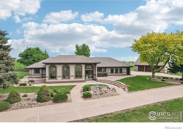 10141 Yellowstone Rd, Longmont, CO 80504 - rear view of house featuring a lawn, a tiled roof, a garage, concrete driveway, and covered porch