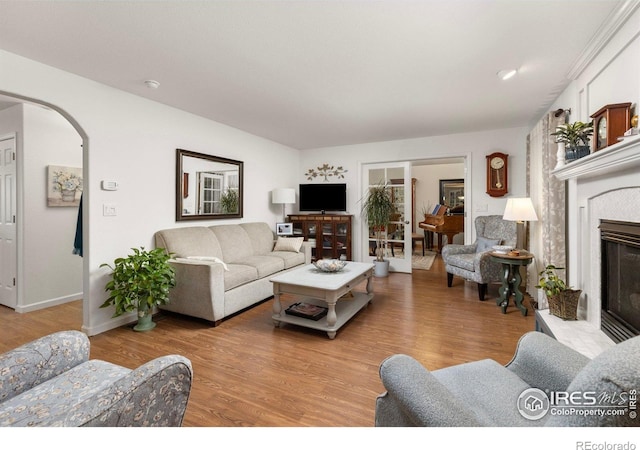 3023 39th Ave, Evans, CO 80620 - living room featuring a tile fireplace, wood finished floors, arched walkways, and baseboards