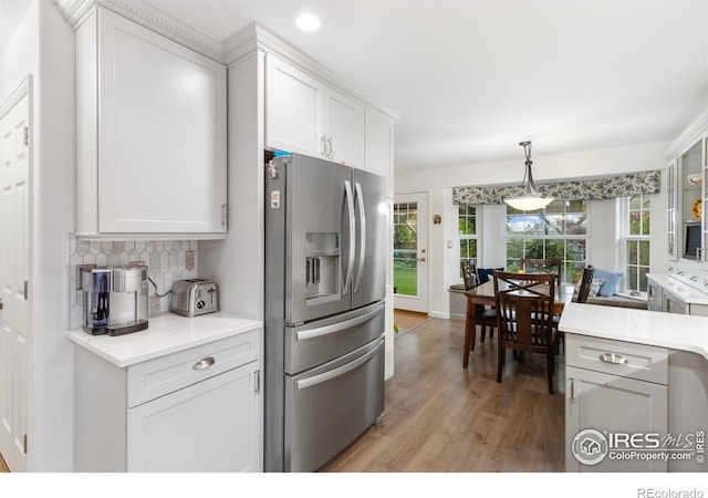 3023 39th Ave, Evans, CO 80620 - kitchen featuring stainless steel fridge with ice dispenser, light wood-style flooring, light countertops, decorative backsplash, and white cabinets