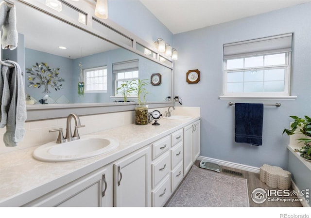 3023 39th Ave, Evans, CO 80620 - bathroom with double vanity, baseboards, tasteful backsplash, and wood finished floors
