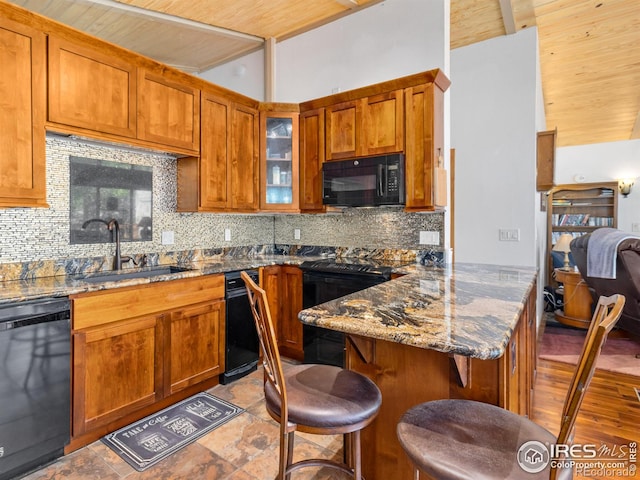 135 Canyon River Rd, Drake, CO 80515 - kitchen with black appliances, a sink, a peninsula, dark stone counters, and a kitchen bar