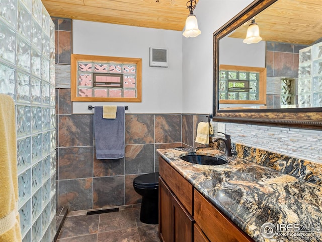 135 Canyon River Rd, Drake, CO 80515 - bathroom with wood ceiling, tile walls, vanity, toilet, and a wainscoted wall