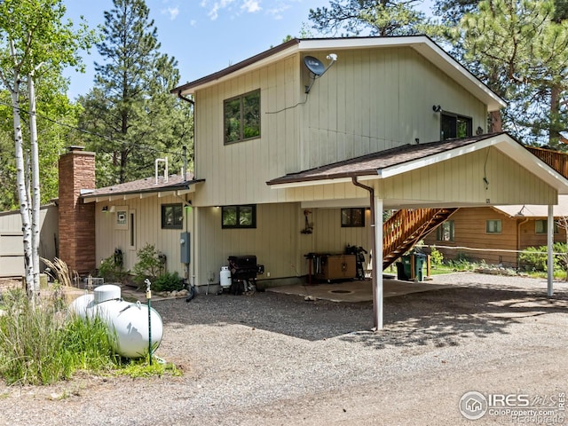 135 Canyon River Rd, Drake, CO 80515 - view of front of property with stairs, a carport, gravel driveway, and a chimney