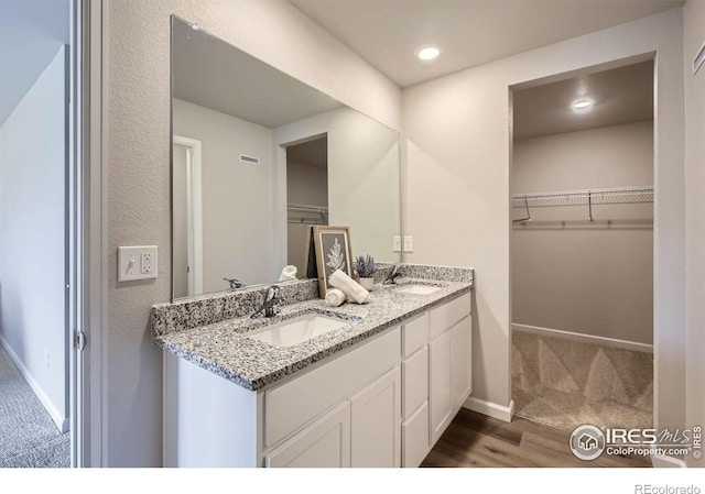 187 Robin Rd, Johnstown, CO 80534 - full bath with double vanity, a spacious closet, wood finished floors, baseboards, and recessed lighting