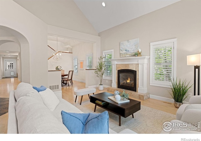 1509 Poplar Ave, Boulder, CO 80304 - living room featuring a chandelier, wood finished floors, high vaulted ceiling, a tile fireplace, and arched walkways