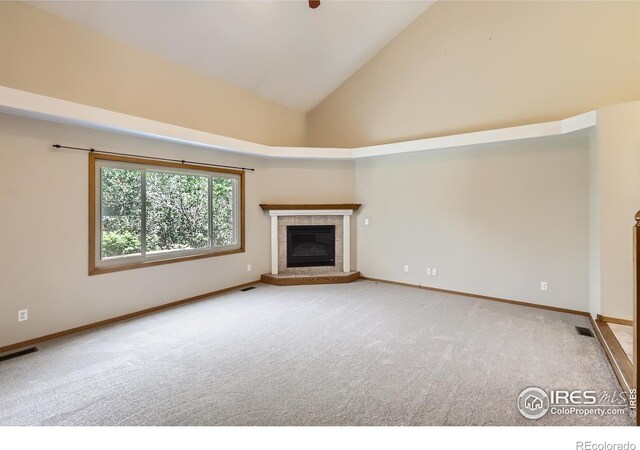 379 E 41st Ct, Loveland, CO 80538 - unfurnished living room featuring a tiled fireplace, carpet, high vaulted ceiling, and baseboards