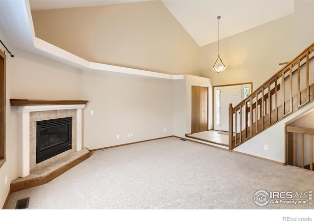 379 E 41st Ct, Loveland, CO 80538 - unfurnished living room featuring high vaulted ceiling, carpet floors, baseboards, a fireplace, and stairway